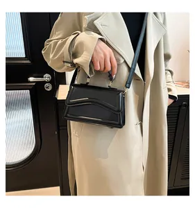Detail of black leather crossbody bag with wave texture and metallic handle connector