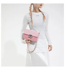 Detail view of pink crossbody bag with woven texture, metal clasp and chain strap