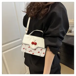 Macro detail of cute cherry print and 3D cherry ornament on white crossbody square bag
