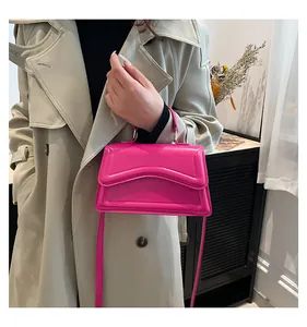 Detail of candy pink glossy leather handbag with wave embossing on the flap and gold lock