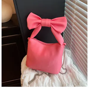 Detailed view of pink bow handle handbag with silver chain strap on lace fabric