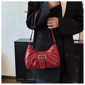 Detalle de bolso de hombro en cuero sintético rojo con diseño plisado y hebilla