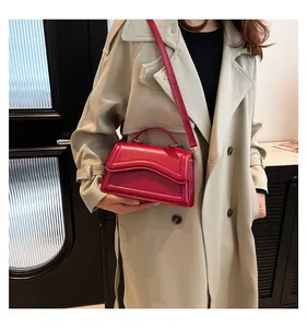 Detail of hot pink crossbody bag with wavy flap design and matching leather strap