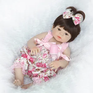 Détail d'une poupée reborn avec cheveux bruns et tenue en dentelle florale sur tapis doux