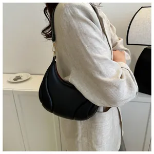 Gros plan d'un sac sous le bras noir en demi-lune avec matelassage plissé et boucle dorée