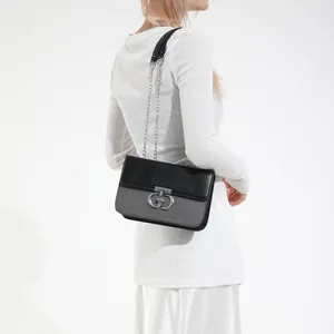 Elegant black and grey crossbody bag with silver chain strap and buckle on model