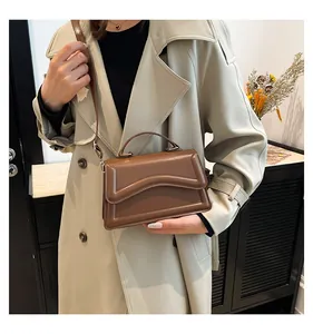 Detail of a brown crossbody bag featuring wave-patterned flap and fine leather texture