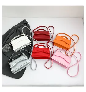 Detail view of colorful candy-toned leather crossbody bags with curved stitching on flap