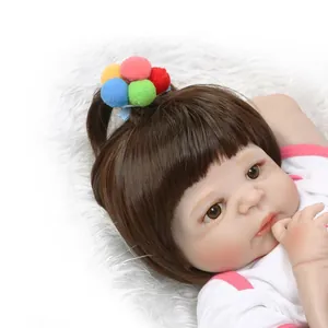 Realistic reborn baby doll with brown hair and colorful pompom headband in pink outfit