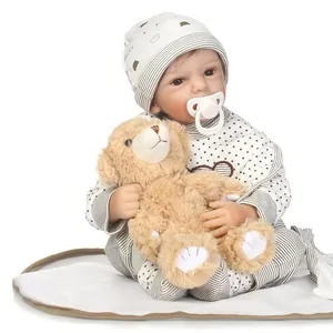 Realistic reborn baby doll in striped outfit with plush bear and white pacifier