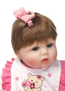 Detailansicht der rosa Glitzer-Haarschleife und Bärenstickerei auf dem Puppenoutfit