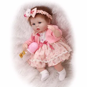 Realistic reborn baby doll in pink floral dress with matching cardigan and feeding bottle