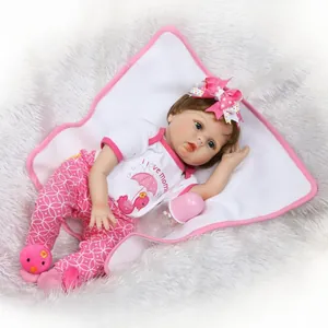 Realistic reborn baby doll with blue eyes and pink outfit set on plush white carpet