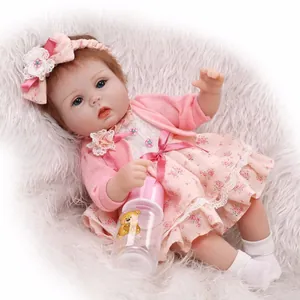 Reborn baby doll with blue eyes and pink floral outfit on white plush mat background