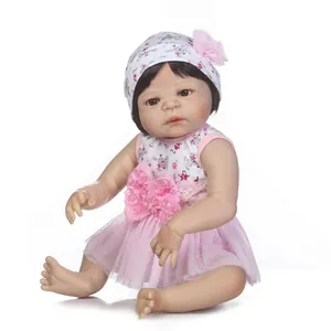 Realistic reborn baby doll in floral pink dress and matching hat on white background