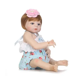 Poupée bébé reborn réaliste avec cheveux bruns et tenue motif fraise sur fond blanc