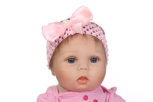 Close-up of reborn baby doll head with pink bow headband and blue eyes details