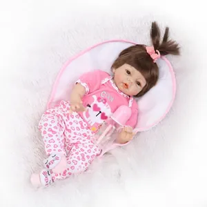 Lifelike soft vinyl reborn baby doll in pink cat outfit with bottle on plush rug