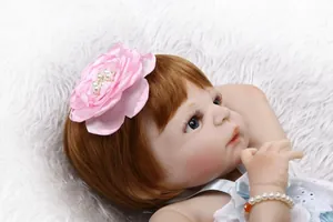 Détail d'une fleur en satin rose et bracelet de perles sur une poupée bébé reborn