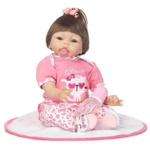 Lifelike reborn baby doll in pink cat outfit with bottle and pacifier on white cushion