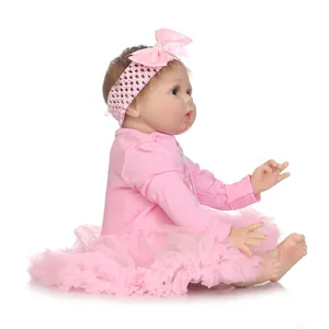 Lifelike reborn baby doll in pink tutu dress and bow headband on white background
