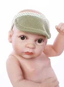 Gros plan d'une poupée bébé en silicone avec yeux marrons et chapeau à carreaux vert
