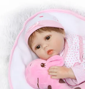 Nahaufnahme einer lebensechten Reborn-Puppe in Rosa mit Plüsch-Giraffe und Babykleidung