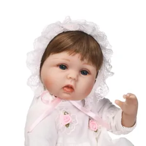 Poupée nouveau-né réaliste avec yeux bleus et robe en dentelle sur fond blanc pur