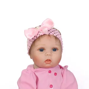 Realistic reborn baby doll with blue eyes and pink knit headband on white background