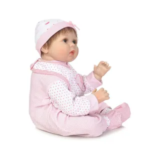 Realistische Reborn-Babypuppe mit braunem Haar im rosa-weiß gepunkteten Outfit mit Hut