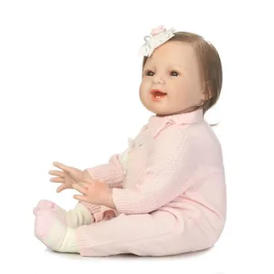 Lifelike reborn baby doll in pink knit romper with lace headband on white background