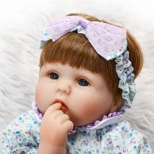 Poupée réaliste Reborn avec yeux bleus et tenue florale bleue sur fond en peluche blanc