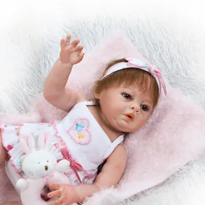 Lifelike reborn baby doll in lace floral dress with a plush rabbit toy on soft rug