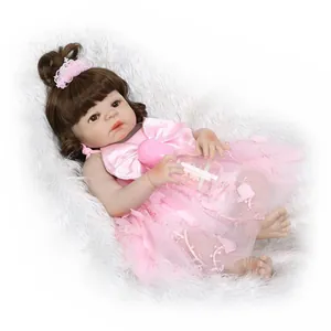 Lifelike reborn baby doll in pink lace dress with crown and bottle on plush white rug