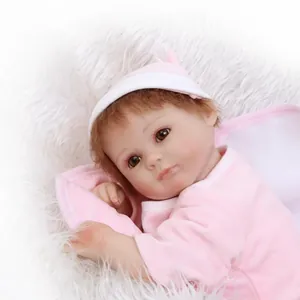 Poupée bébé reborn réaliste en tenue rose avec cheveux bruns sur peluche blanche