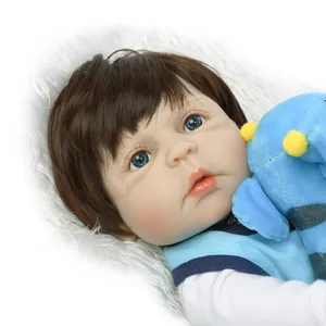 Lifelike newborn baby doll with blue eyes and brown hair wearing a blue outfit