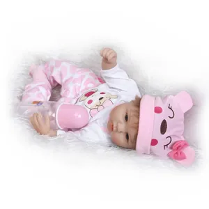 Realistische Reborn babypop van 40 cm in roze berenpak met flesje op een pluche tapijt