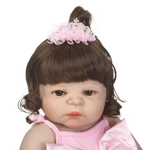 Lifelike reborn baby doll with brown curly hair in pink lace crown and strap dress