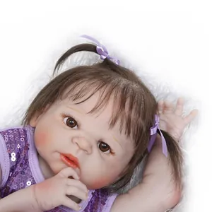 Realistic reborn baby doll with brown pigtails and purple sequin outfit on white fur