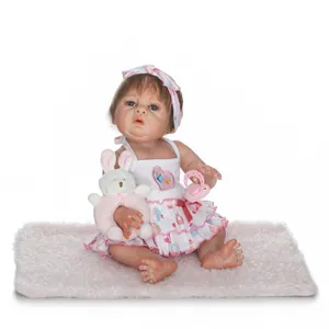 Lifelike reborn baby doll in heart dress with plush bunny toy on soft pink rug