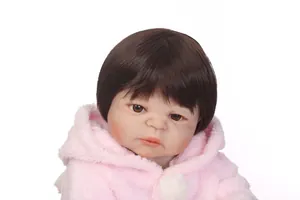 Dettaglio di una bambola reborn realistica con occhi marroni e giacca di peluche rosa