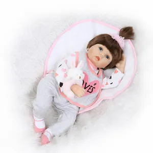 Poupée bébé reborn réaliste avec cheveux bruns, yeux bleus et lapin en peluche sur tapis