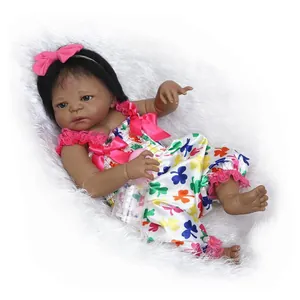 Realistic black newborn baby doll in floral outfit with bottle on white plush background