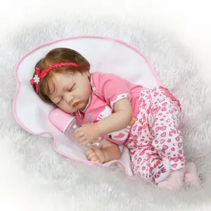 Poupée Reborn réaliste endormie en tenue rose avec biberon sur un tapis en peluche