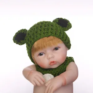 Reborn baby doll in green frog themed knitted hat and outfit with blonde hair