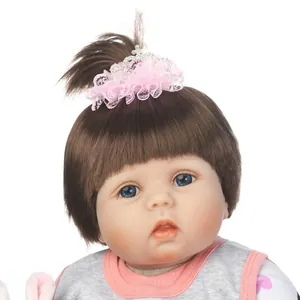 Poupée bébé reborn réaliste avec cheveux bruns et couronne en dentelle rose sur blanc