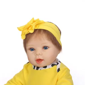 Muñeca bebé reborn realista con ojos azules y diadema floral amarilla en primer plano