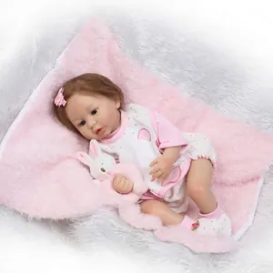 Realistische Reborn babypop in roze polkadot outfit met pluche konijn op wit bont
