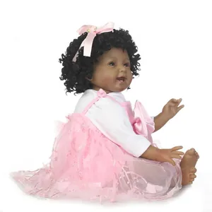 Realistische schwarze Babypuppe mit lockigem Haar im rosa Spitzenkleid auf Weiß