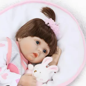 Poupée bébé Reborn réaliste avec cheveux bruns et tenue à cœurs roses tenant un lapin